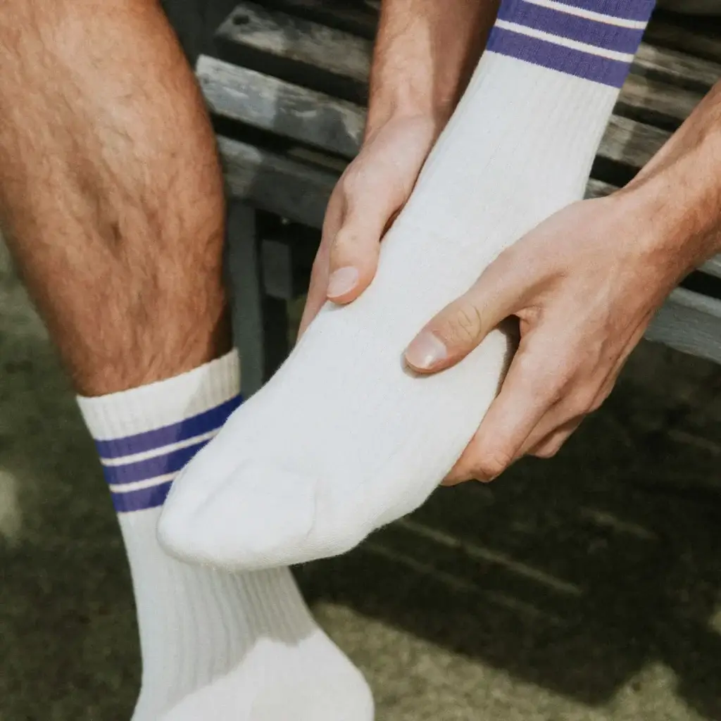 Man holding his foot in discomfort, illustrating joint pain commonly associated with the causes of gout disease.