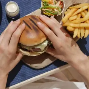 Person eating a burger, one of the high purine foods that may cause gout